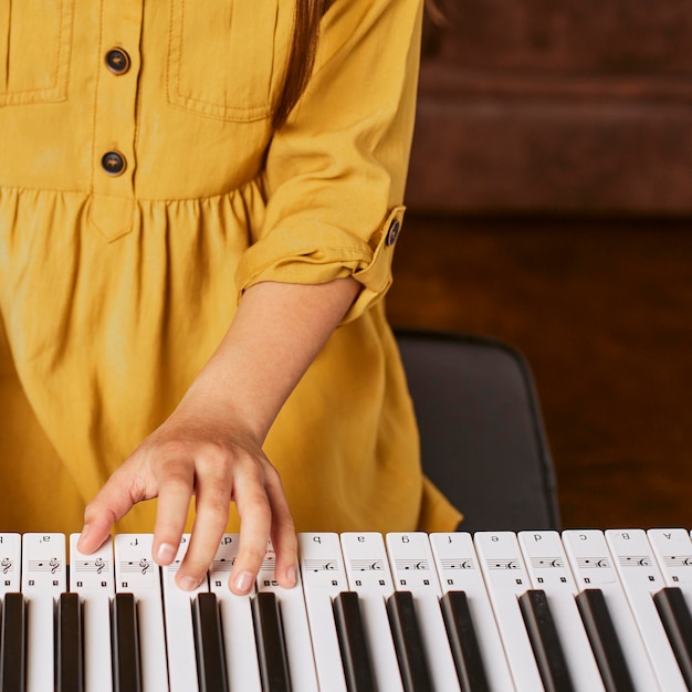 Young girl learning how to play electronic keyboard at home