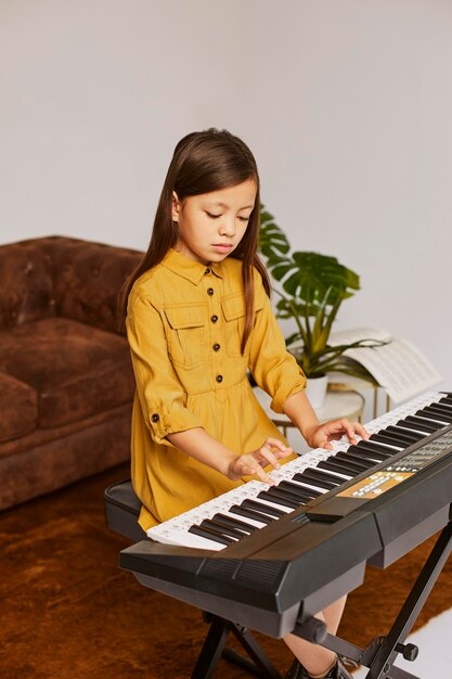 Young girl learning how to play electronic keyboard at home