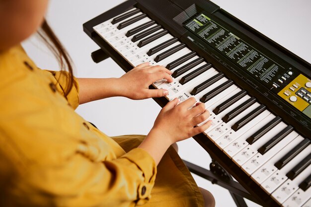 Young girl learning how to play electronic keyboard at home