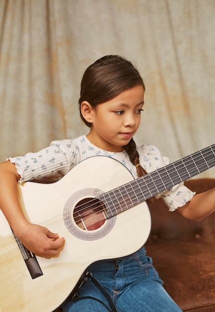 집에서 기타를 연주하는 방법을 배우는 어린 소녀