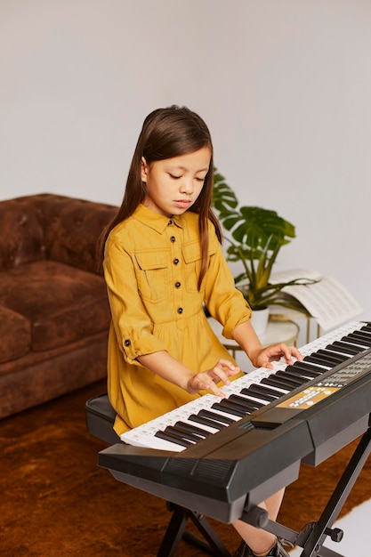 無料写真 自宅で電子キーボードを演奏する方法を学ぶ少女