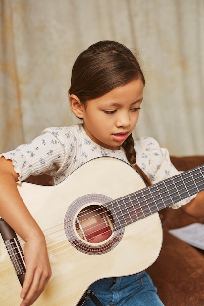 Бесплатное фото Молодая девушка учится играть на гитаре дома