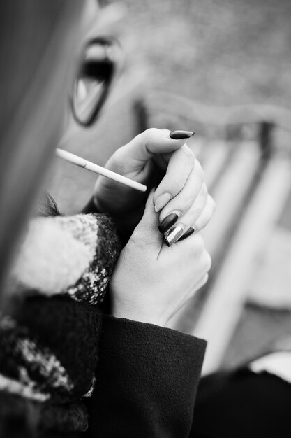 Young girl lighting cigarette outdoors close up Concept of nicotine addiction by teenagers