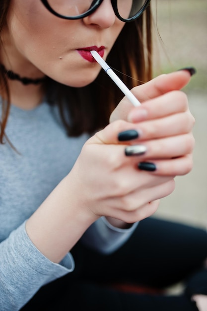Young girl lighting cigarette outdoors close up Concept of nicotine addiction by teenagers