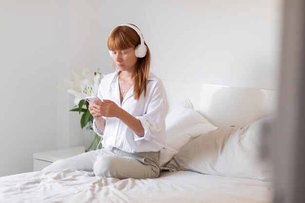 Молодая девушка слушает музыку в постели Цветочная лилия в помещении
