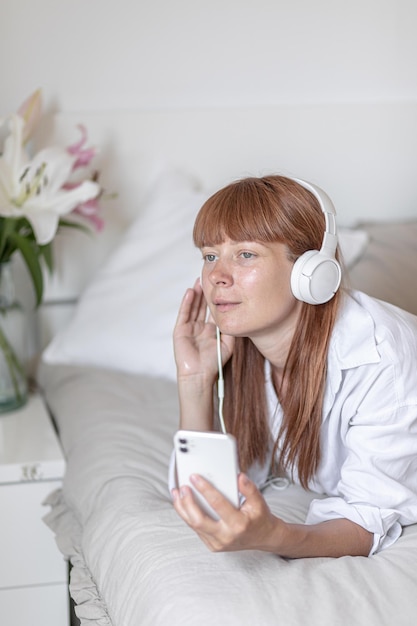 Молодая девушка слушает музыку в постели Цветочная лилия в помещении