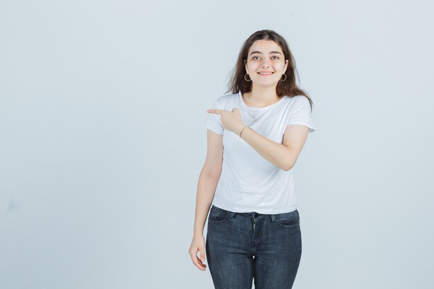 Молодая девушка смотрит в сторону в футболке, джинсах и выглядит веселой. передний план.