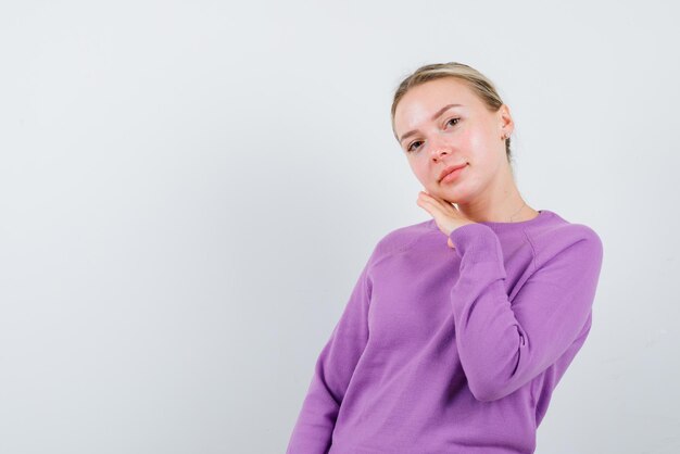 Young girl looking at the camera and holding her hands under her chin on white background