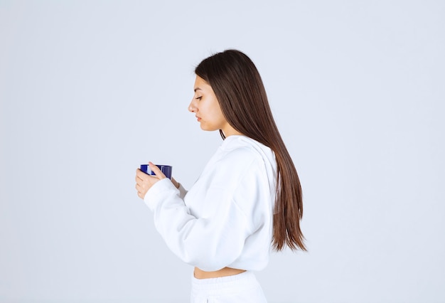 young girl looking at a cup on white-gray background.