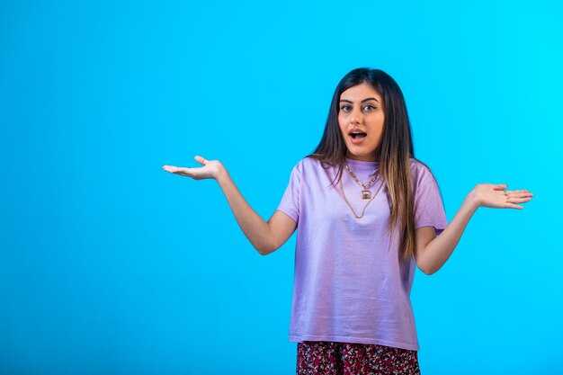 Young girl looks surprized on blue background. 