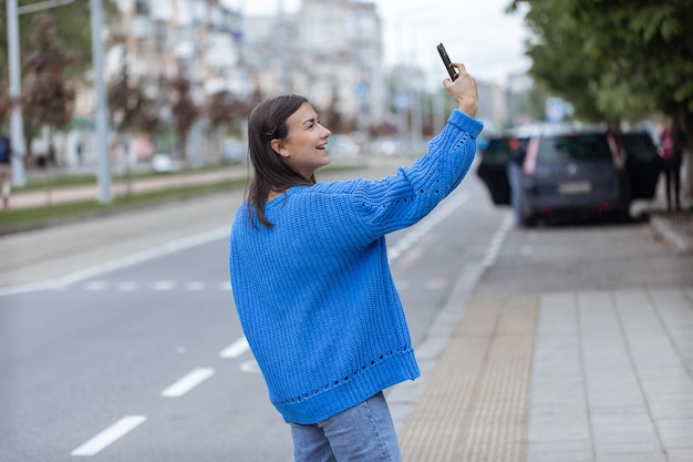 若い女の子が通りの電話カメラで自分撮りをします。