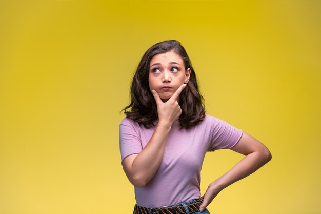 Young girl makes thinking hand sign at her chin.