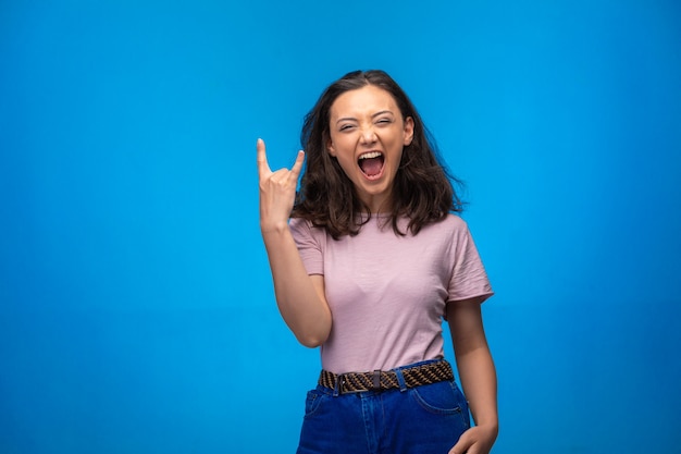 Young girl making peace symbol with fingers and laughs positively.