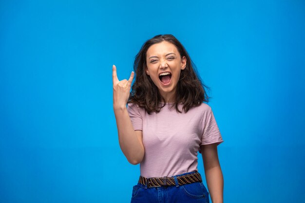 Young girl making peace symbol with fingers and laughs positively. 