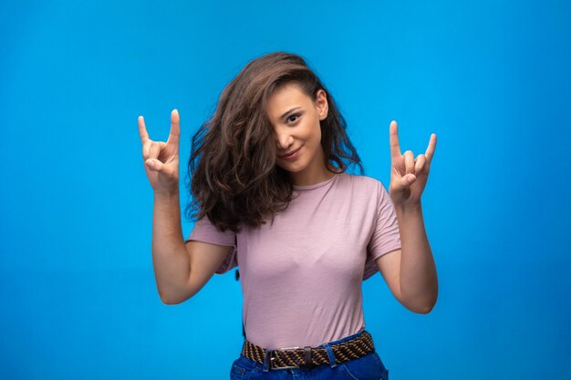 Young girl making peace symbol with fingers and looks positive.