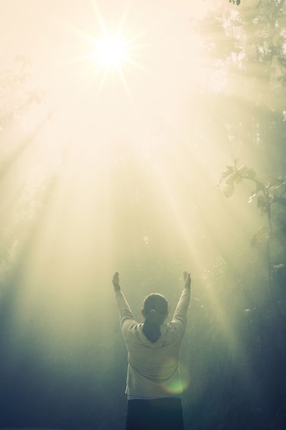 Young girl meditate in the green forest with sunlight