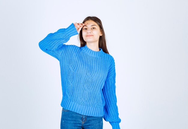 young girl model in blue sweater holding hand near forehead .