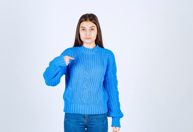young girl model in blue sweater pointing at herself.