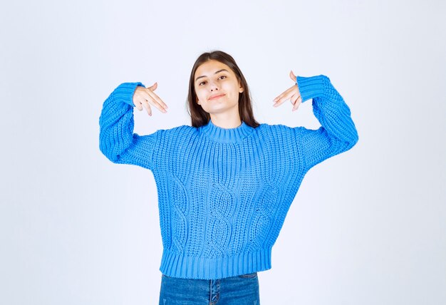 자신을 가리키는 파란색 스웨터에 어린 소녀 모델.