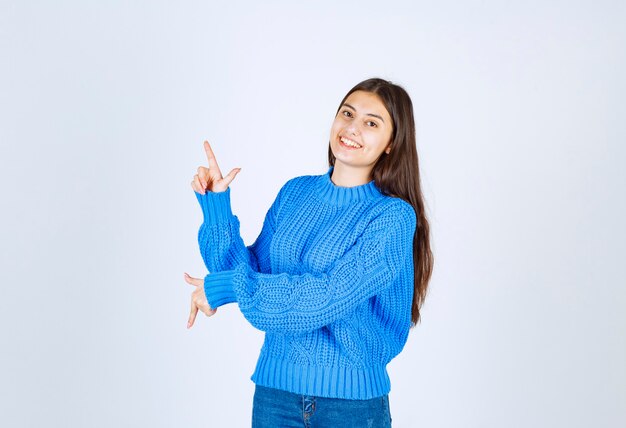 модель молодой девушки в синем свитере, указывая вверх и вниз.