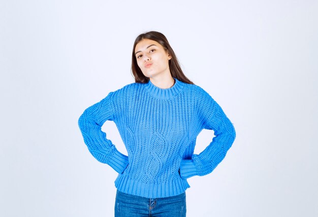 модель молодой девушки в синем свитере позирует с руками на бедрах.