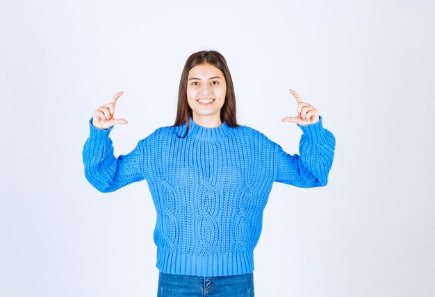 파란색 스웨터 서 고 흰색 회색에 포즈에 어린 소녀 모델.