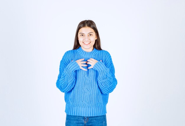 白灰色で立ってポーズをとる青いセーターの若い女の子モデル。