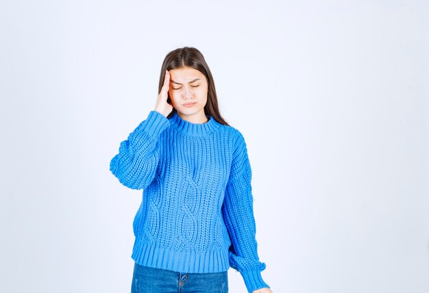 young girl model in blue sweater standing and posing on white-gray.