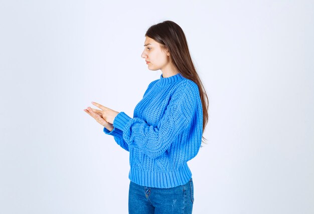 молодая девушка модель в синем свитере стоя и позирует на бело-сером.
