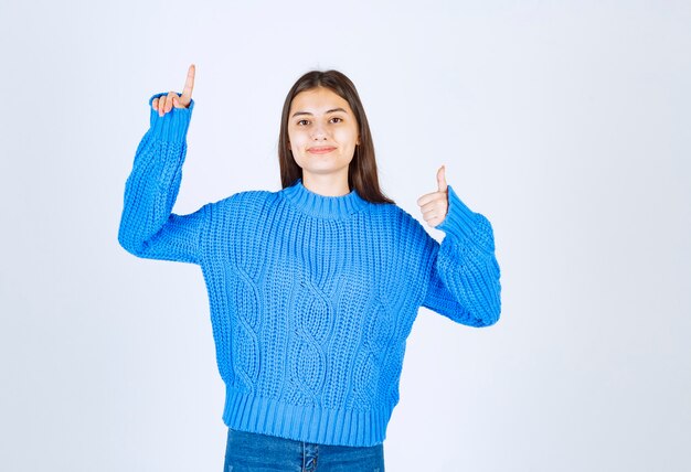 young girl model pointing up and showing a thumb up .