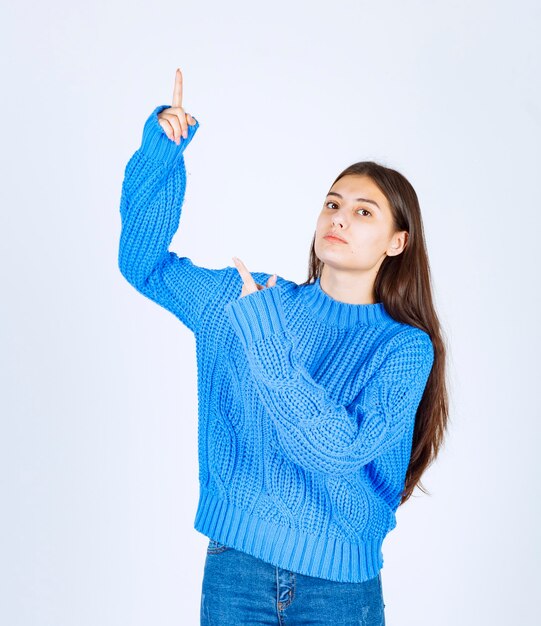 young girl model pointing up on white wall.