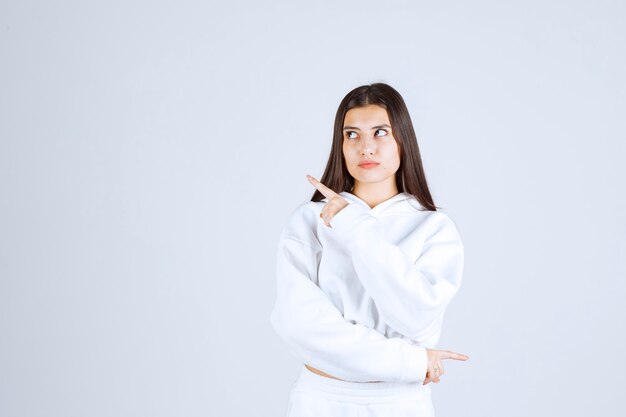 young girl model pointing up with index fingers.