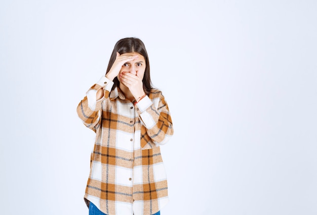 a young girl model standing and covering nose . 