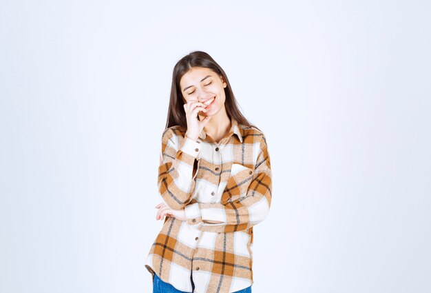 young girl model standing on white-gray wall.