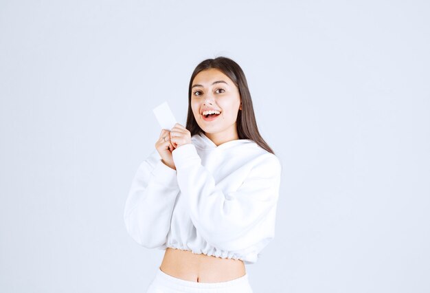 young girl model with a card on white-gray background.