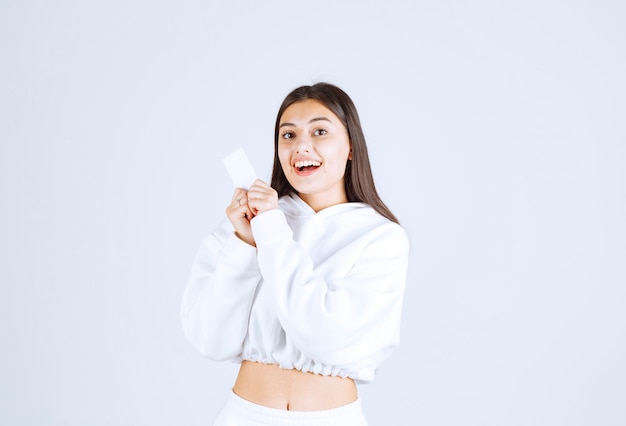 young girl model with a card on white-gray background.