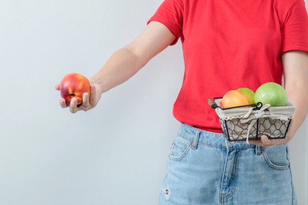 Young girl offering a fruit basket in the hand.