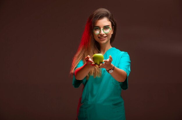 手に青リンゴを提供する少女。