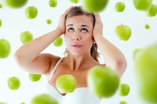 Young girl overwhelmed by diet, surrounded by apples.