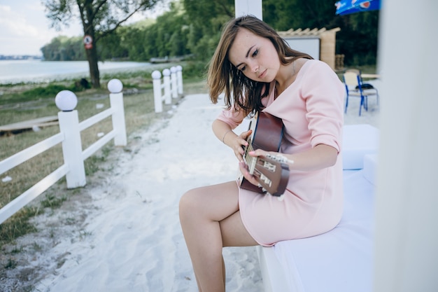 Young girl in a pink dress playing a guitar