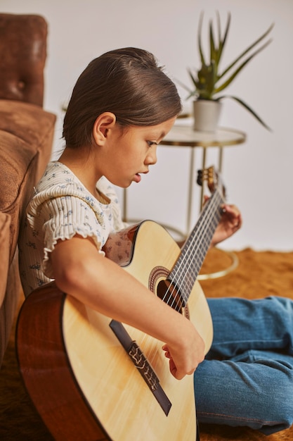 집에서 기타를 연주하는 어린 소녀