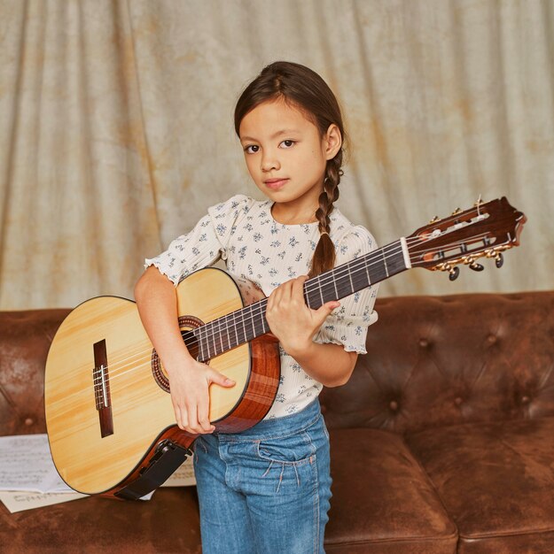집에서 기타를 연주하는 어린 소녀