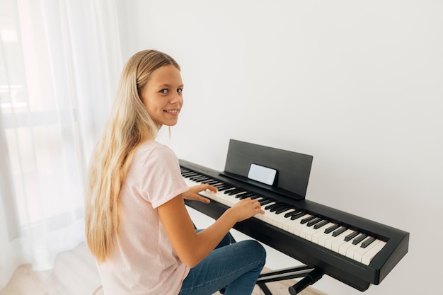 Free photo young girl playing keyboard instrument at home