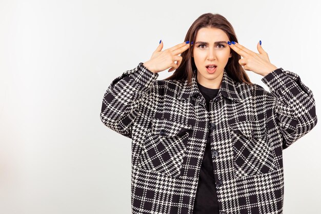 Young girl point her fingers to her head and stand on white background