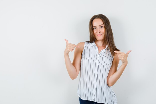 自分を指して、Tシャツ、ジーンズ、正面図で笑っている少女。