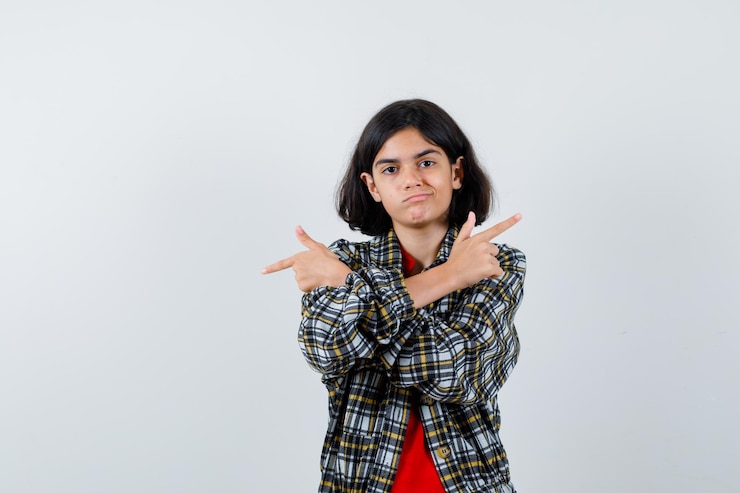 मुफ़्त फोटो young girl pointing opposite directions in checked shirt and red t-shirt and looking serious. front view.