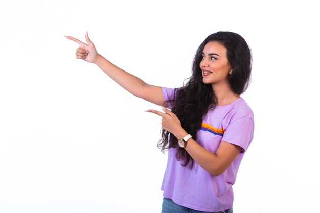 Young girl pointing at something and making presentation on white background