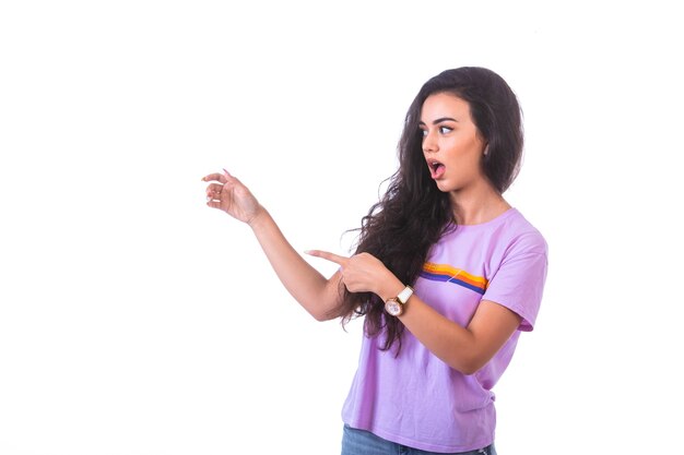 Young girl pointing at something on the right and looks surprized.