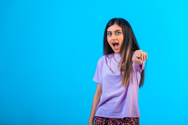 Young girl pointing at something with finger gest.