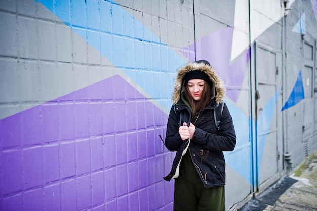 Young girl posed against colored wall in cold day